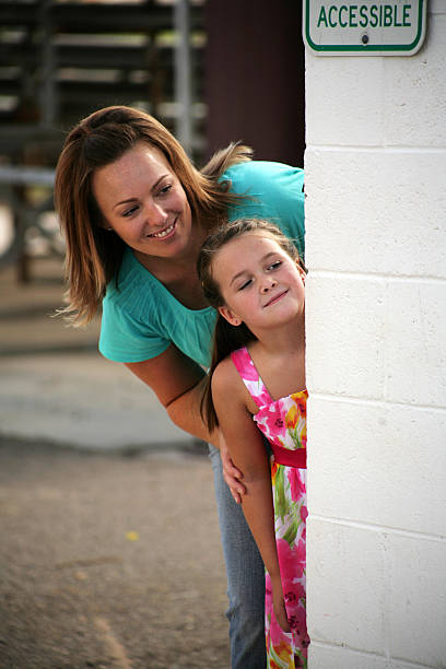 Corner Sneak Cute mother and daughter peeking around a corner. looking around stock pictures, royalty-free photos & images