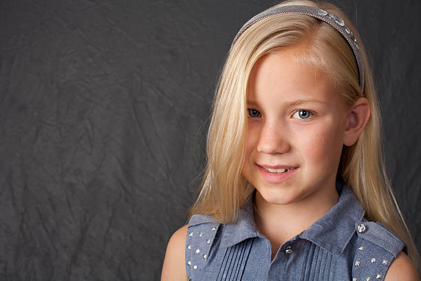 8 year old blonde girl in studio setting smiles to camera.View More: