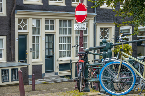 Netherlands. Amsterdam summer canal embankment with traditional houses and parked bicycles. Under the prohibition sign there is an inscription in Dutch except for