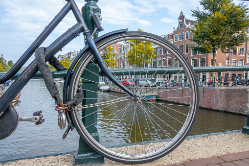 Netherlands. Autumn day in Amsterdam. The wheel of a bicycle parked on the bridge and the canal embankment