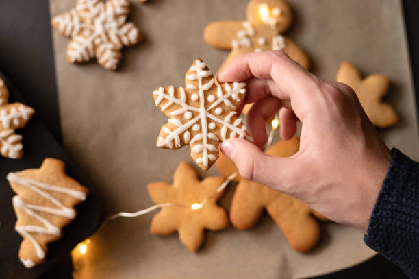 istock Hand holding snowflake shape gingerbread cookie decorated with sugar icing. Christmas holiday celebration, traditional family cooking 1828572493