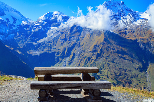 The famous mountain road Grossglognerstrasse. Wooden table and picnic benches. Austria. The Hohe Tauern Park. Snowy mountain peaks covered with clouds.