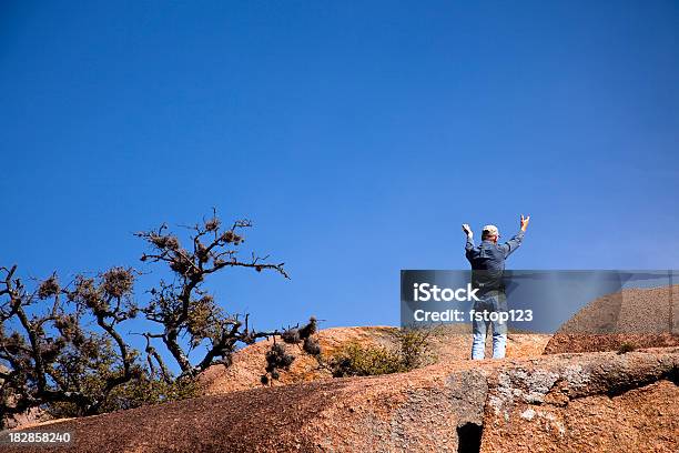 Man On High Rocks With Hands Raised To The Heavens Stock Photo - Download Image Now