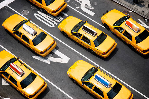 Fleet of Yellow New York City Taxi Cabs from Above Fleet of yellow taxi cabs make their way down the street of Broadway in New York City in view from above yellow taxi cab stock pictures, royalty-free photos & images
