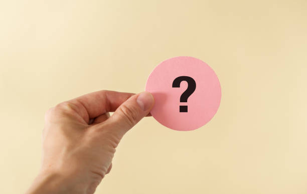 istock Hand holding out a business card with question mark on yellow background 1828597228
