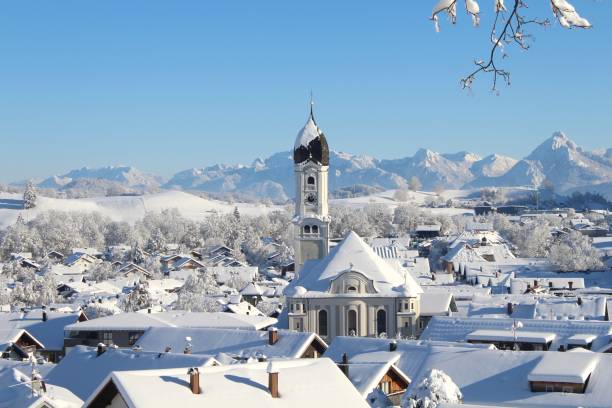 聖アンドレアス教区教会とアルプスを背景にした雪に覆われたネッセルヴァングの眺め。ネッセルヴァングはウィンタースポーツのバケーションリゾートでもあります。アルプスピッツェで� - church in the snow ストックフォトと画像