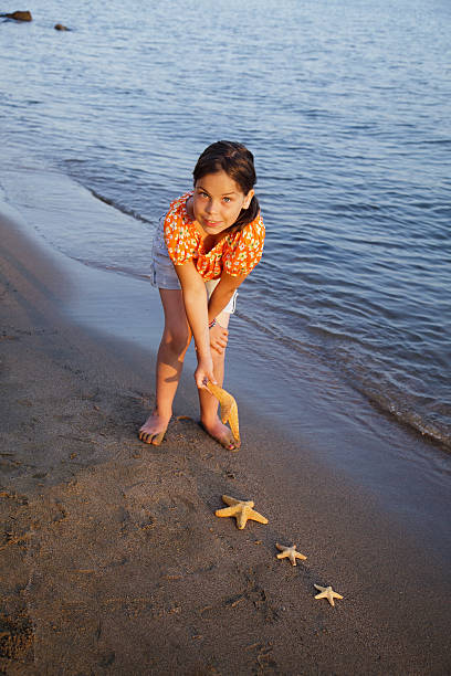 istock Girl on the shoreline, gathering star fish. 182860951