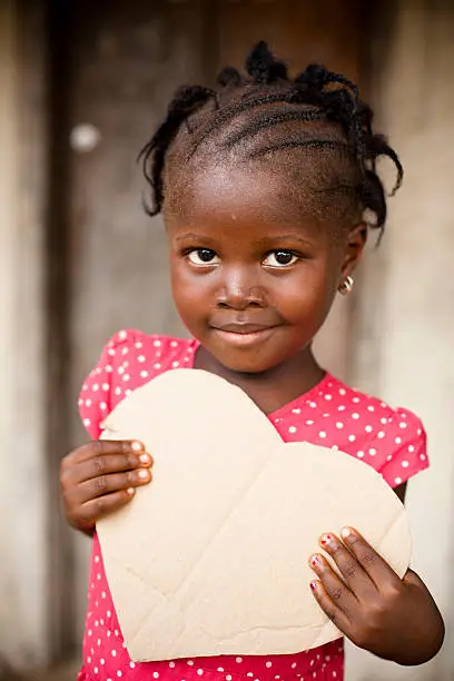 Photo of African child holding heart shaped cardboard sign