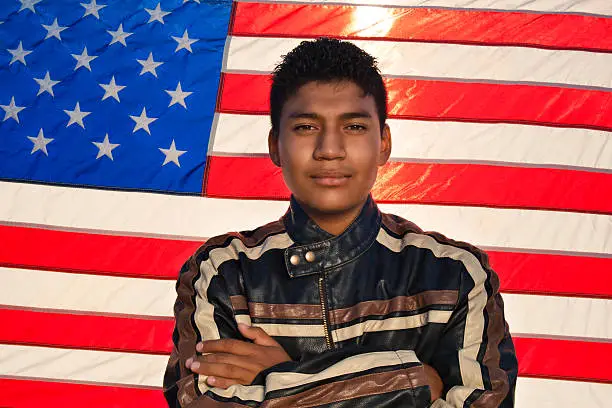 Young Latin man in front of the American flag.