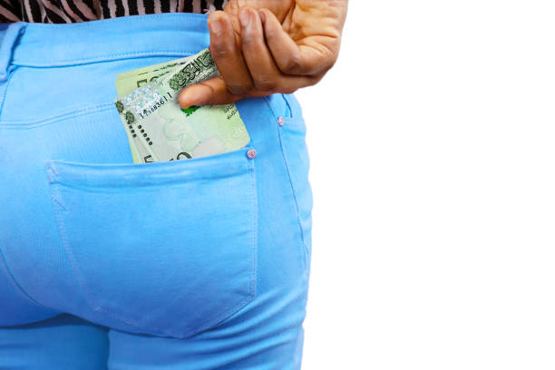 istock Black lady putting few Libyan dinar notes into her back pocket. Removing money from pocket, hold money 1828620604