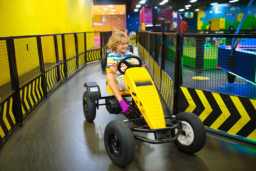 Kids on carting track. Go-kart fun for children. Boy racing in a go kart car on birthday party in indoor playground. Car race adventure.