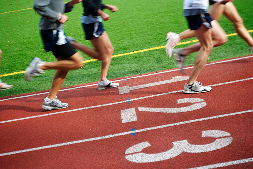 Runners speed by on running track with lanes marked 1, 2, and 3