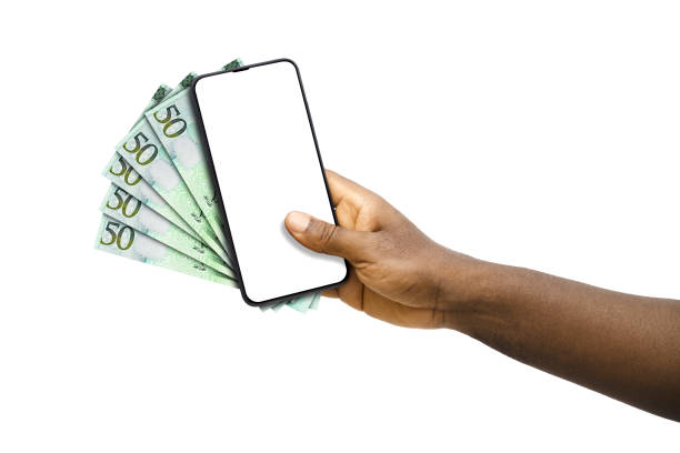 istock Black hand holding mobile phone with blank screen and Libyan dinar notes 1828629695