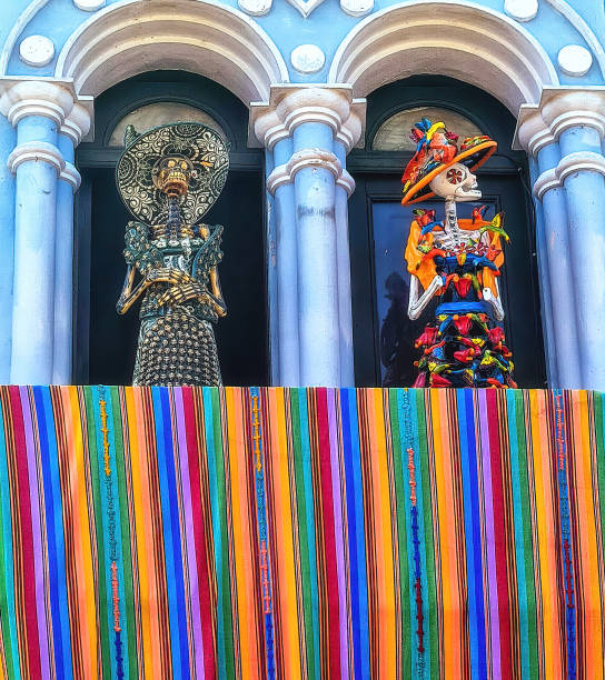 skeletons in a hat and bright Mexican clothes stands on the balcony. Handmade skeleton figurine to commemorate Death Day in Mexico.