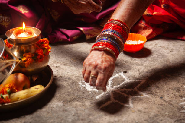 istock An Indian woman is making an Auspicious Hindu design pattern (rangoli). 1828640862