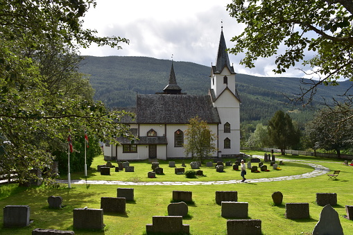 Un cimetière dans l’herbe et une église blanche, en Norvège