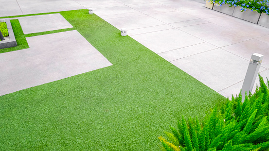 Artificial turf with gravel stone pavement decoration and ornamental plant in Home Gardening area, high angle view with copy space