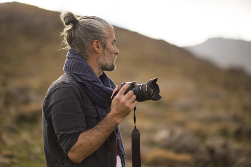 man walking around hills and foothills in autumn and taking photographs