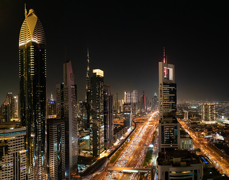 A stunning night view of Sheikh Zayed road from a roof top point, with traffic visible and beautiful skyscrapers surrounding the avenue.