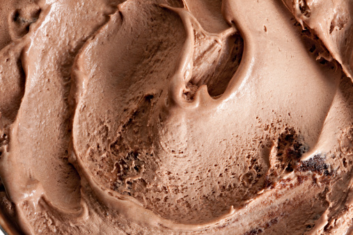 A macro swirl of chocolate ice cream with chunks of brownie in it.