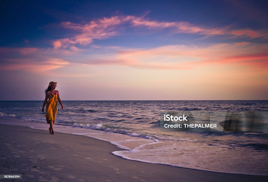 woman walking on the beach woman walking on an almost empty beach in naples florida at sunset Adult Stock Photo