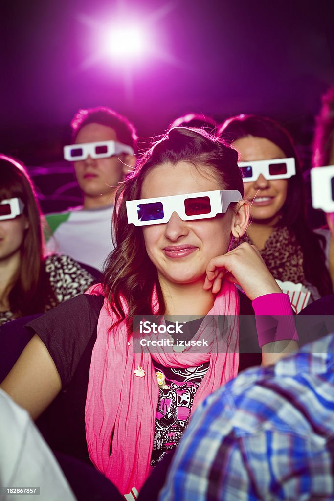 Young people in 3D move theater "Group of young adult people wearing 3D glasses, sitting in the cinema  and watching 3D move. Teenage girls sitting in the middle smiling." 3-D Glasses Stock Photo
