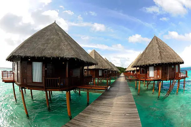 Typical waterbungalows with a footbridge and crystal clear water early morning on the maldives. July 2010.