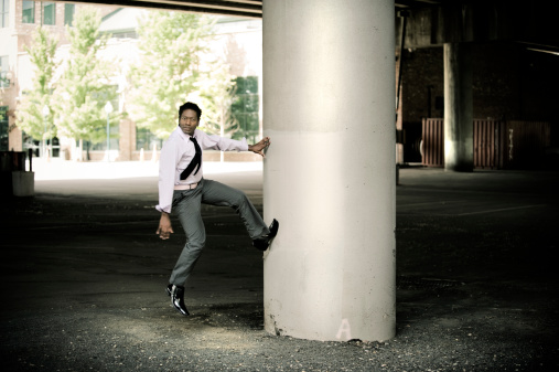Business man is jumping against a column.