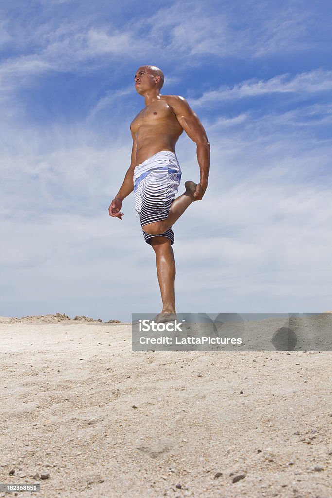 Hombre de raza mixta de estiramiento en la arena - Foto de stock de 20 a 29 años libre de derechos