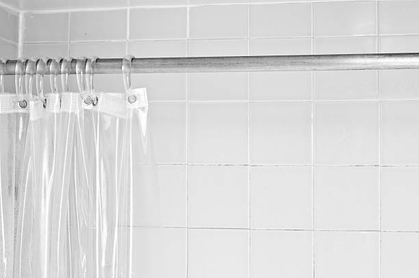 Clear shower curtain with a white tile shower stock photo