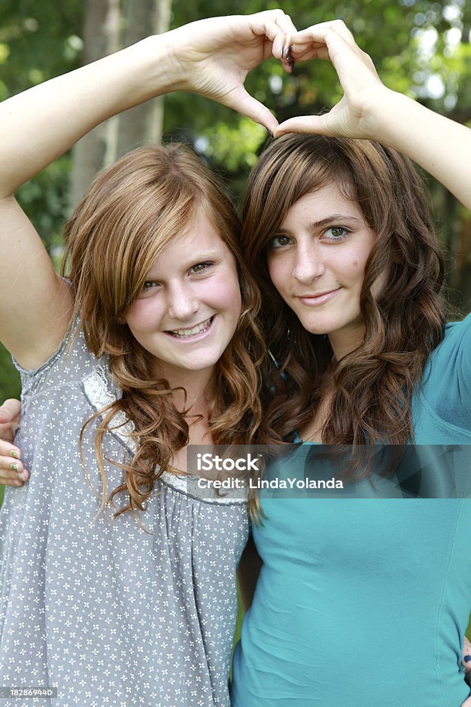 Beautiful Teen Girls Two teenage girls make a heart with their hands. Adolescence Stock Photo