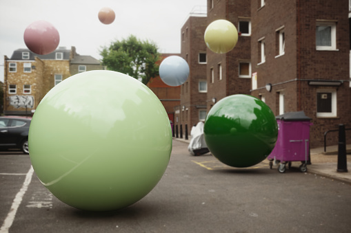 Multi colored and reflective spheres flying in the city. (3d render)