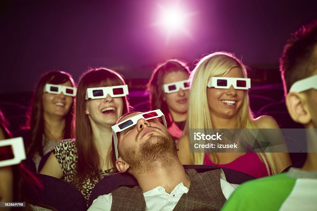 Young people in 3D move theater "Group of young adult people wearing 3D glasses, sitting in the cinema  and watching funny 3D move. Girls are laughing young adult man sleeping." 3-D Glasses Stock Photo