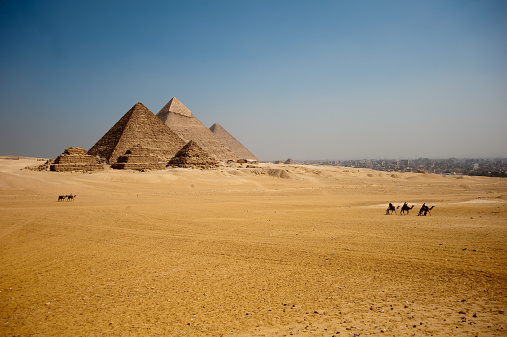 Giza pyramids in Egypt. Tourists ridding camels in the foreground.