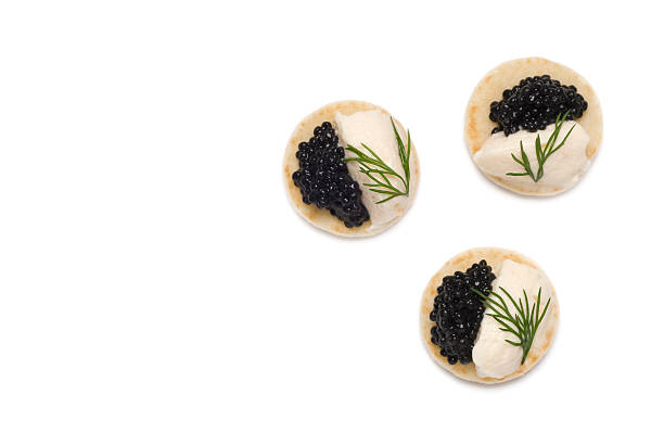 Three Caviar and dill Appetizers A studio shot of three Caviar and salmon mousse canapés with a dill garnish isolated on a white background blini photos stock pictures, royalty-free photos & images