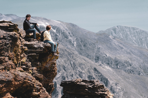 Hikers rest on a cliff edge.