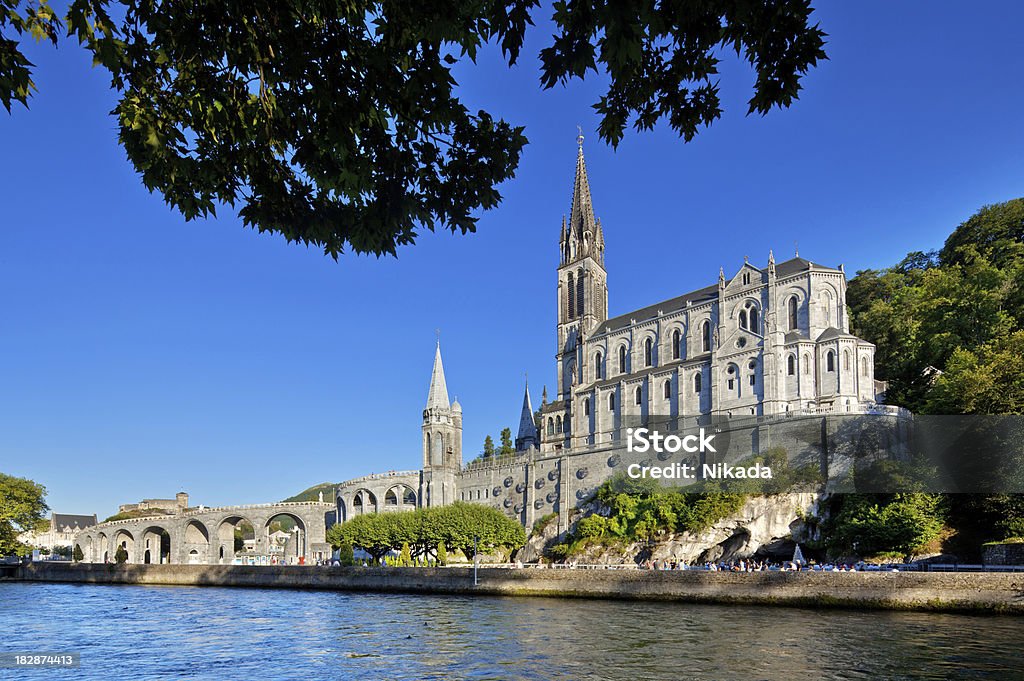 Cathedral of Lourdes, France "Cathedral of Lourdes, FranceBelow the Basilique behind the trees the Grotte de MassabilleLourdes is a small market town lying in the foothills of the Pyrenees, famous for the Marian apparitions of Our Lady of Lourdes that are reported to have occurred in 1858 to Bernadette Soubirous." Lourdes - France Stock Photo
