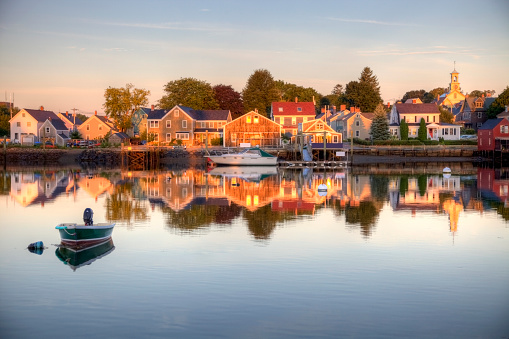 Portsmouth is a city in Rockingham County, New Hampshire.  It is a historic seaport and popular summer tourist destination. Photo of a calm waterfront surrounded by a soft morning light . Portsmouth is the third oldest city in the USA  and is only  60 miles from Boston