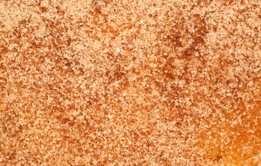 Close up of a cake topped with butter and sprinkled with cinnamon sugar.