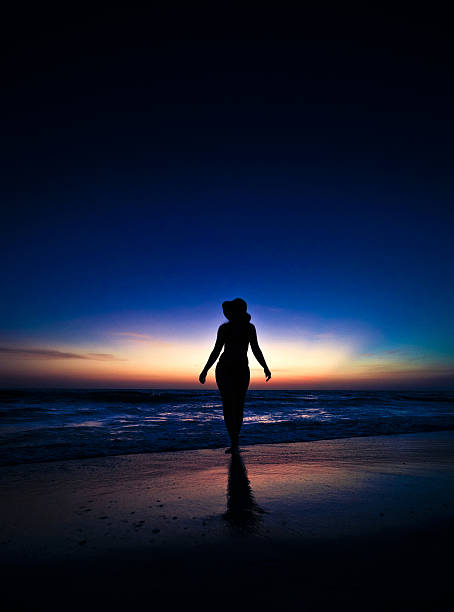 istock woman silhouetted on the beach 182876196