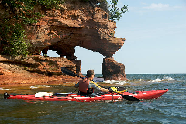 Sea Kayaking on Lake Superior "Man, age 57, kayaking among the Apostle Islands on Lake Superior just off the shore of Wisconsin." bayfield county stock pictures, royalty-free photos & images