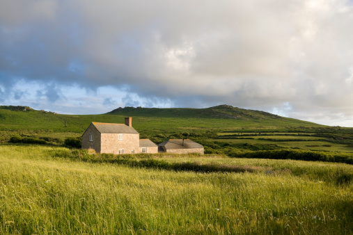 Country farm house in a grassy field near moorland