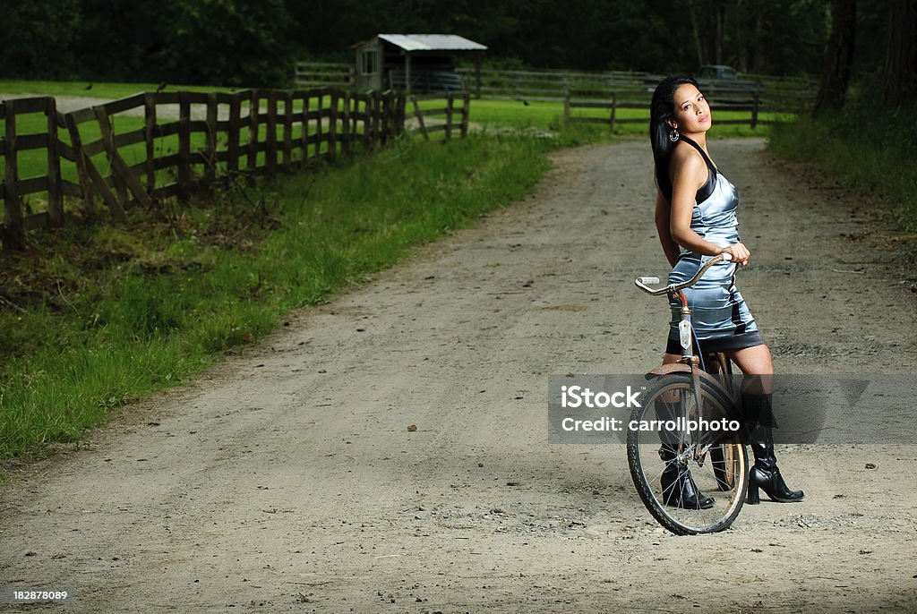 Donna in un vestito blu sulla bicicletta-Strada in terra battuta - Foto stock royalty-free di Sporco