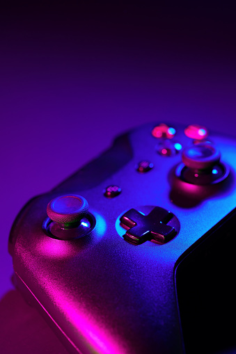 Gaming joystick on black background in neon light close up