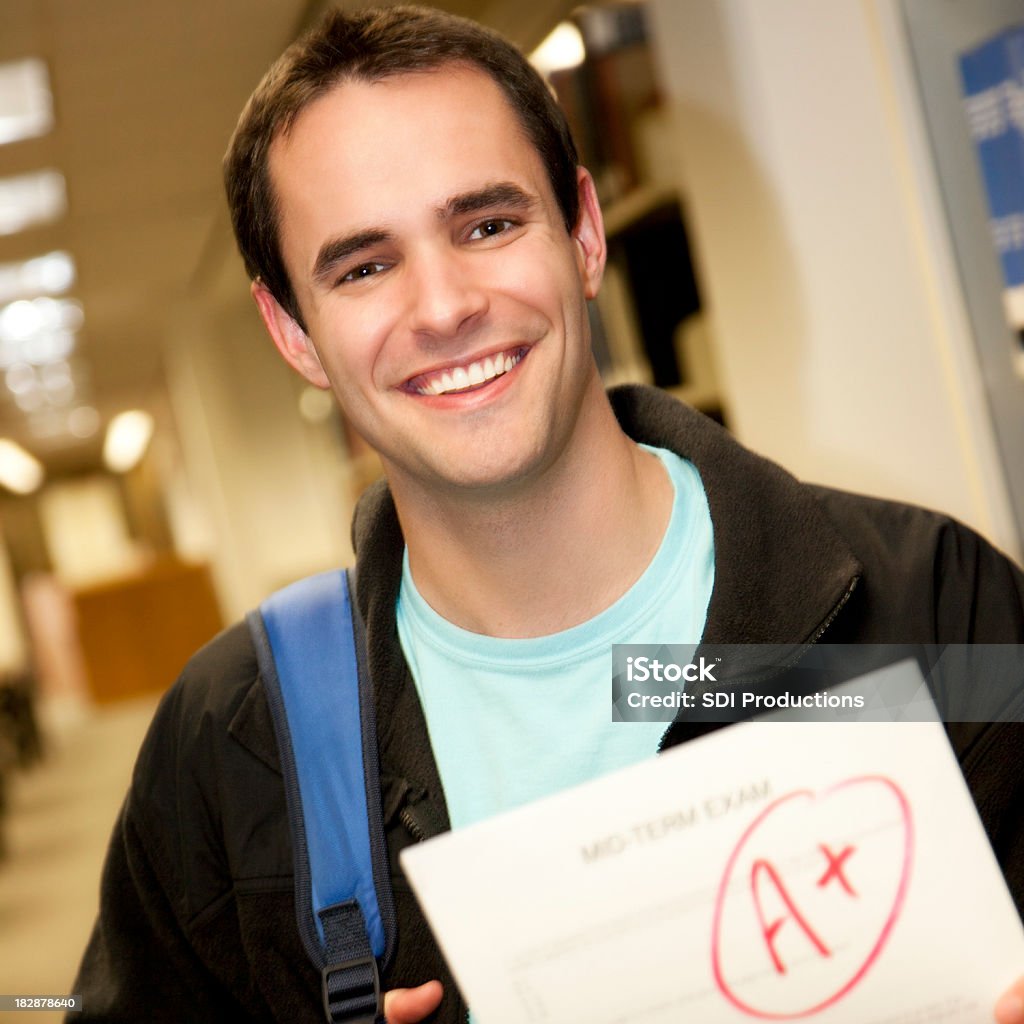 Université heureux étudiant tenant un examen papier - Photo de 20-24 ans libre de droits