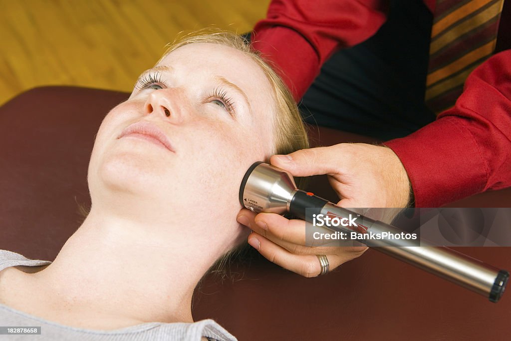 Doctor Administering Cold Laser Therapy Treatment to Female Patient’s Face  Alternative Therapy Stock Photo