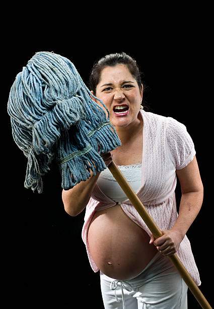 angry, indispensável estômago mulher segurando uma esfregona enquanto yelling. - bitching imagens e fotografias de stock