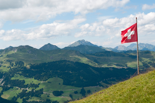 A Swiss flag over the Swiss Alpes in Summer