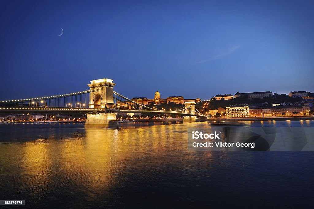 Budapest at night,  Szechenyi Chain Bridge. "Capital of Hungary, view of the Chain Bridge (SzAchenyi LA!nchA-d) over the Danube (Duna), with the Buda castle in the background. Sunset shot, clear summer day. With lots of negative space for your text and copy." Advertisement Stock Photo