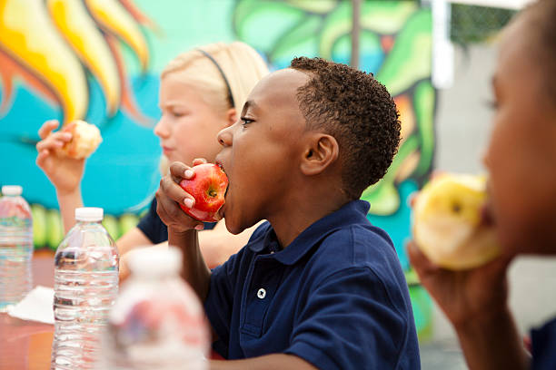 中の学生のランチです。 - child eating apple fruit ストックフォトと画像